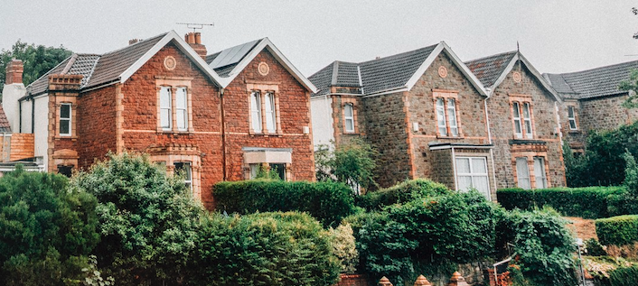 Foto van charmante twee-onder-een-kapwoningen met bakstenen gevels en omliggende groene heggen